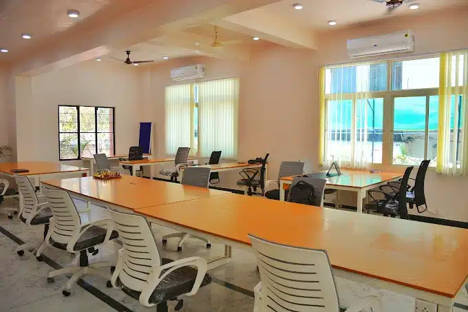 Meeting room with AC, chairs, big table, mechanized curtains, fan, warm lights, and clients working in an inspiring environment at coworking space in Vaishali Nagar, Jaipur.