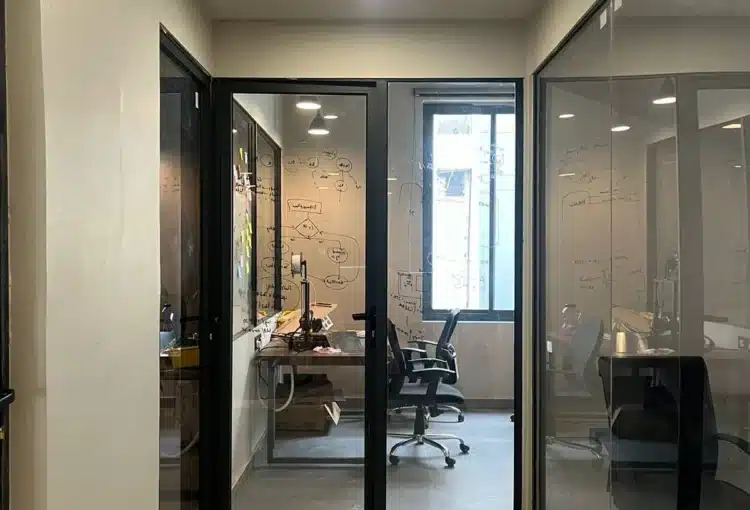 "Glass door entry with chairs, table, and AC at RAW coworking space in Vaishali Nagar, Jaipur."